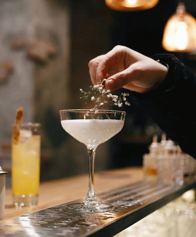 person holding clear wine glass with white liquid